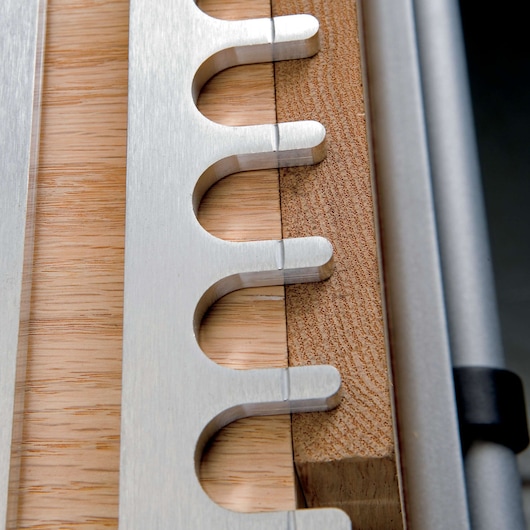 Close-up of a metal dovetail jig positioned on a piece of wood, used for precise woodworking joinery.