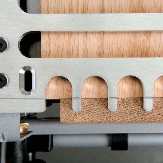 Close-up of a metal dovetail jig with wooden boards positioned inside, used for precision woodworking and joinery.