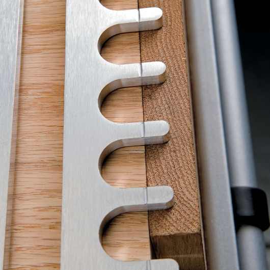 Close-up view of a PORTER-CABLE dovetail jig with metal guide and wooden pieces, used for creating precise woodworking joints.