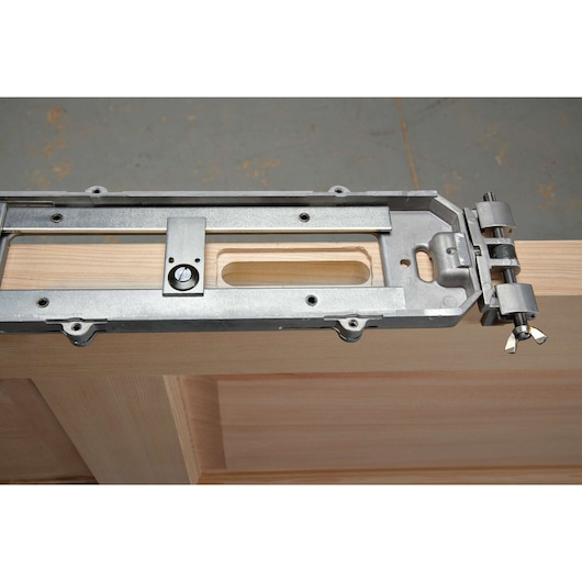 A PORTER-CABLE door lock installation kit is clamped onto the edge of a wooden door, showing the metal guide and hardware used for precise cutting and drilling.