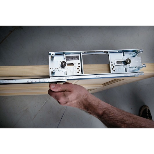 A close-up view of a PORTER-CABLE dovetail jig tool being used to measure and set on a wooden board, with a person's hand adjusting the tool.