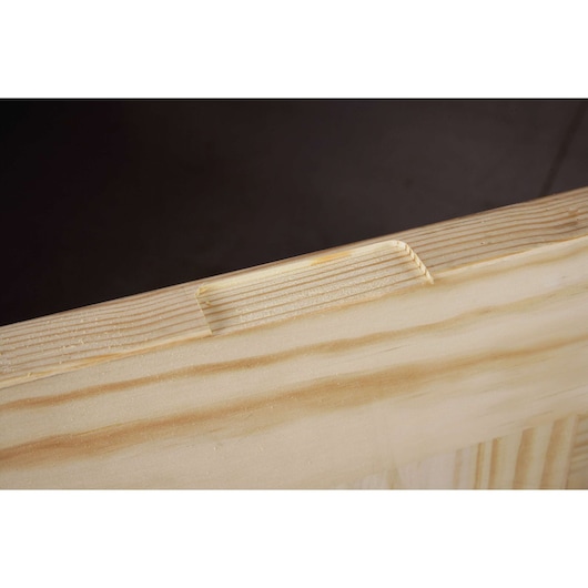 Close-up view of a wooden plank with a groove cut along the edge, showing the texture and grain of the wood.