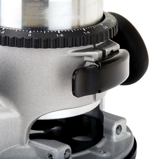 Close-up view of a metallic power tool, showing a part of a router base and adjustment knob with marked increments. The tool has a silver and black finish.