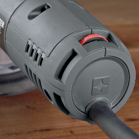 Close-up view of the PORTER-CABLE 7345 power tool, showing its gray body, ventilation slots, cable connection, and a visible red adjustment dial on a wooden surface.