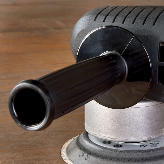 Close-up view of a PORTER-CABLE electric sander, showing the handle and part of the sanding base on a wooden surface.