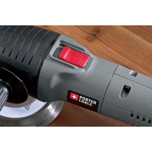 Close-up of a PORTER-CABLE power tool with a gray body and a red switch, placed on a wooden surface.