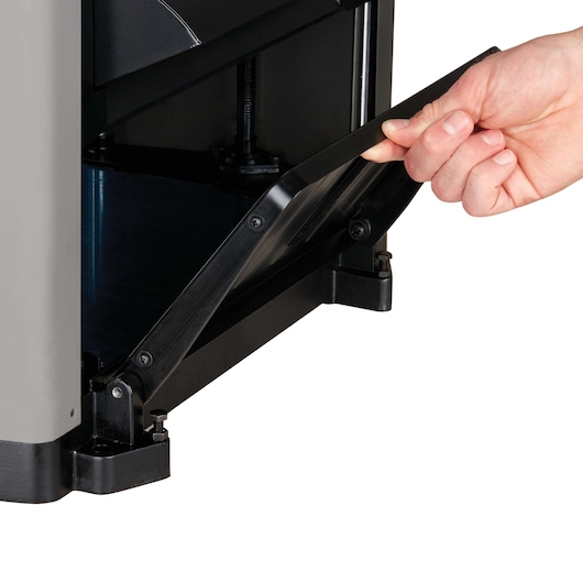 A close-up of a hand opening the lower front access panel of a PORTER-CABLE machine, showing internal mechanical parts.