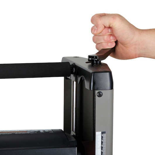 A close-up of a hand turning the adjustment handle on the PORTER-CABLE PC305TP thickness planer machine.