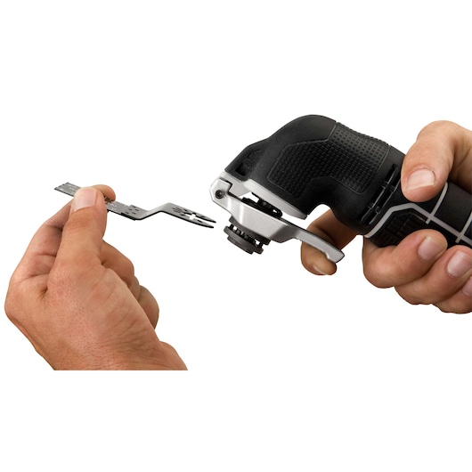 Close-up of hands holding a PORTER-CABLE oscillating tool and a metal attachment blade, showing installation or removal of the accessory.