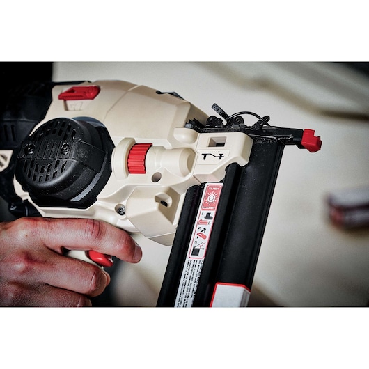Close-up view of a person holding a PORTER-CABLE PCC790LA cordless nail gun, highlighting the tool's controls and magazine.
