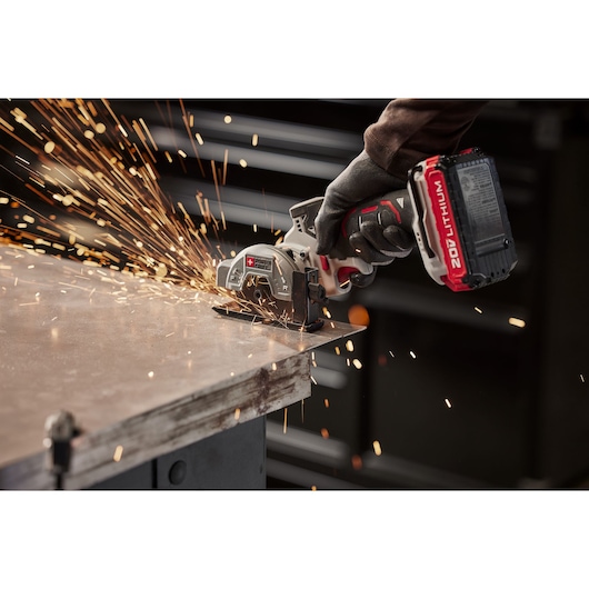 A PORTER-CABLE cordless power tool with a 20V lithium battery is being used by a gloved hand to cut through a metal surface, producing sparks.