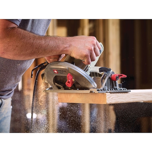 A PORTER-CABLE circular saw being used to cut a piece of wood, with sawdust flying, in a construction or woodworking setting.