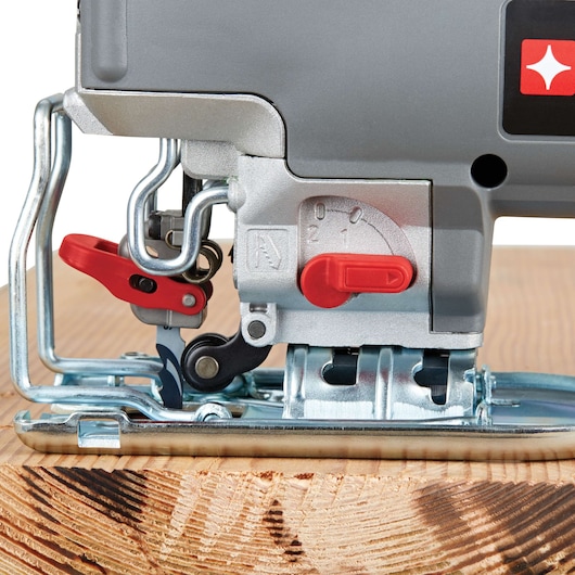 Close-up of a PORTER-CABLE jigsaw saw cutting through a piece of wood, showing the details of the adjustment controls and metal guard.