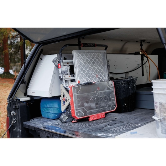 PORTER-CABLE PCE980 tile saw stored in the back of a vehicle, surrounded by other construction tools and equipment.
