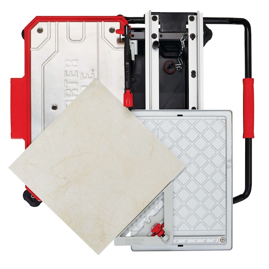Top view of a PORTER-CABLE tile saw with a large beige ceramic tile placed on the cutting platform. The saw has a silver work surface, red handles, and adjustment knobs.