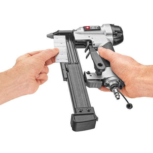 A person is loading a strip of pins into a PORTER-CABLE pneumatic pin nailer, model PIN138, with hands visible holding the tool and the pins against a white background.